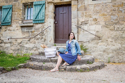 Attractive young woman sitting and posing on ancient stone stairs outdoor