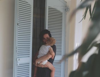 Mother carrying son while standing at doorway