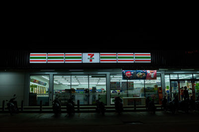 People walking on illuminated city at night