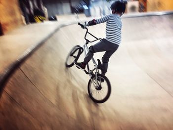 Rear view of boy riding bicycle at skateboard park