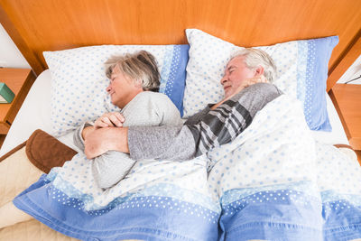 High angle view of senior couple sleeping on bed at home