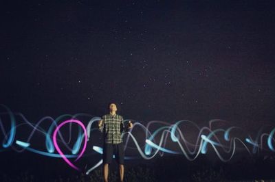 Full length of man with light trails in city at night