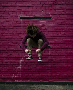 Full length of young woman against brick wall