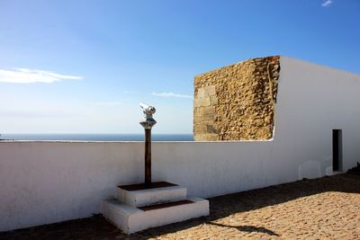 Wall by sea against clear blue sky