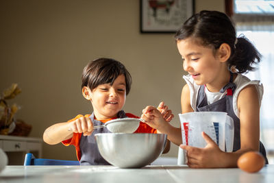 Two happy girls wearing grey aprons baking cookies