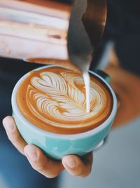 Midsection of person pouring milk in coffee