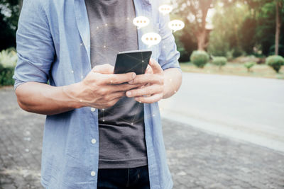 Midsection of man using mobile phone in park