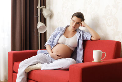 Mother and daughter sitting on sofa at home