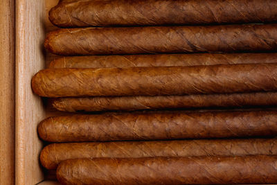 Stack of cigars in humidor on the wooden background