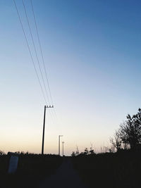 Low angle view of silhouette electricity pylon on field against sky