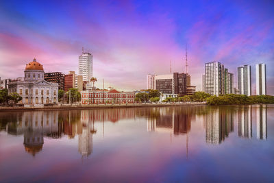 Reflection of buildings in lake against sky in city