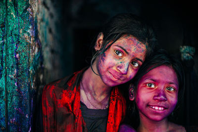 Portrait of smiling sisters with powder paints
