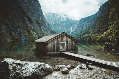 Built structure by rocky mountains against sky