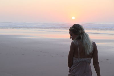 Woman standing at beach during sunset