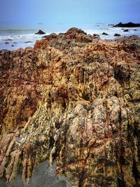 Rock formation on beach against sky
