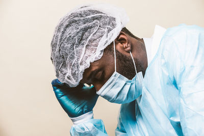 Doctor wearing mask sitting against colored background