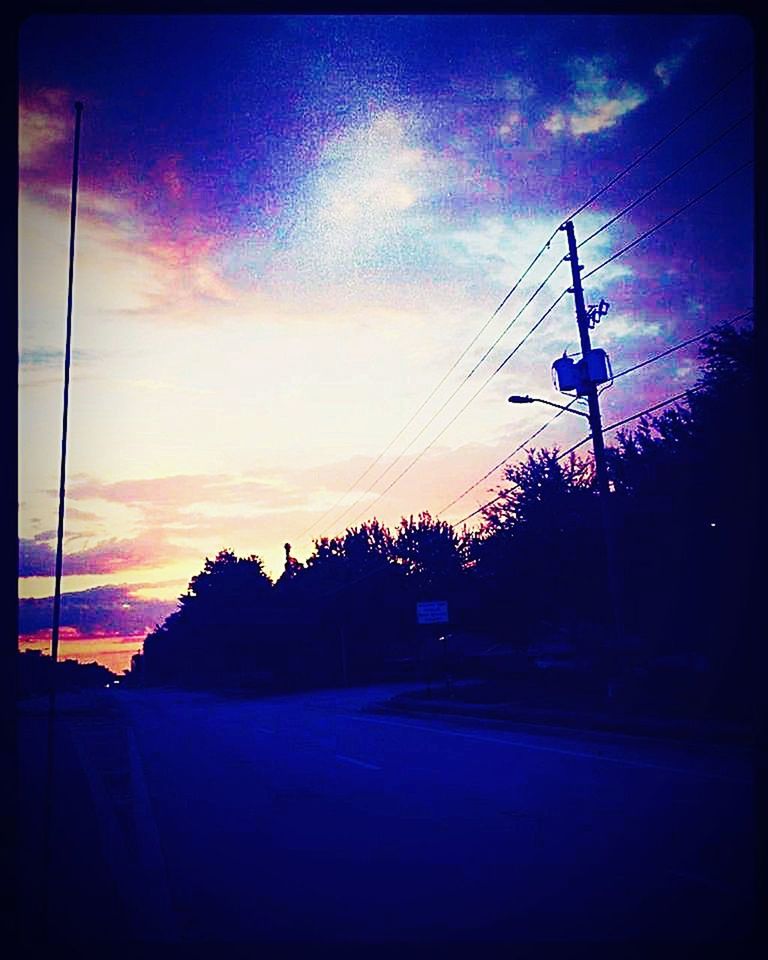 SILHOUETTE OF ELECTRICITY PYLON BY ROAD AGAINST SKY