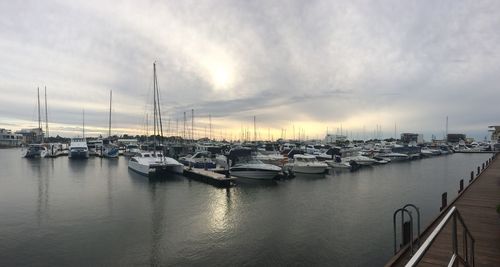 Boats moored at harbor against sky