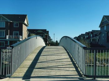 Footbridge amidst buildings against clear sky