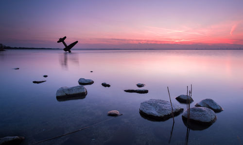 Silhouette man in lake against sky during sunset