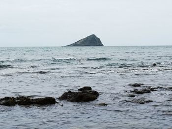 Scenic view of rocks in sea against clear sky