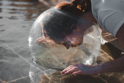 Close-up of woman wearing glass container at lake