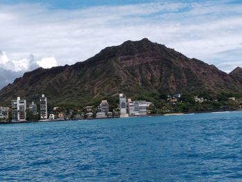 Scenic view of sea by mountain against sky