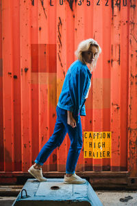 Portrait of woman standing against cargo container