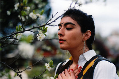 Close-up portrait of woman with flowers on tree