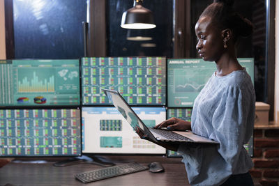 Side view of female trader using laptop in office