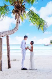 Side view of wedding couple standing on at beach