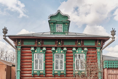 Facade of russian log house with dormer window on roof and carved wooden decorations