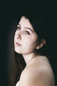 Close-up portrait of a beautiful young woman over black background