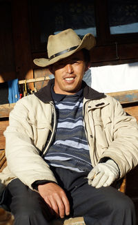 Portrait of mature man wearing hat sitting at barn