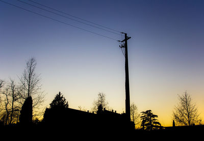 Low angle view of silhouette electricity pylon against sky at sunset