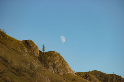 Low angle view of rocks against clear blue sky