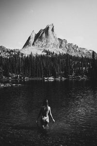 Rear view of young woman wearing bikini standing in lake against clear sky