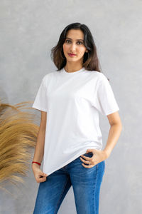 Portrait of young woman standing against wall