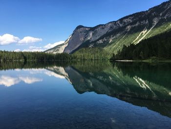 Scenic view of lake by mountains against blue sky