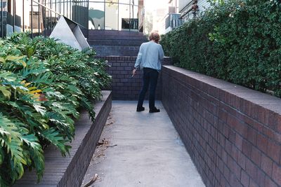 Rear view of man walking on footpath