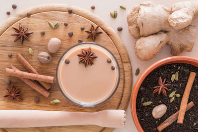 High angle view of tea with ingredients in glass on cutting board over table