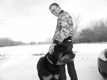 Man smoking cigarette with dog on snow