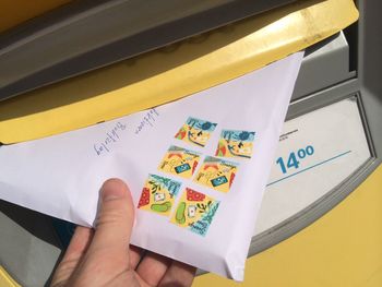 Cropped hand dropping envelope in public mailbox