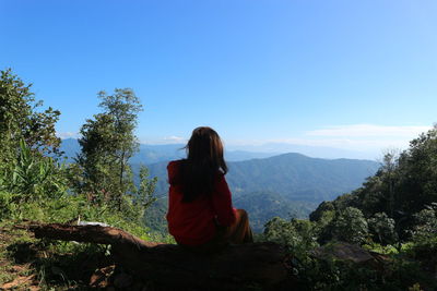 Rear view of woman sitting against sky