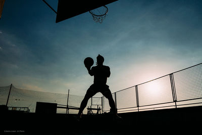 Low angle view of silhouette man playing basketball