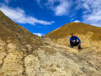 Man standing on rock against sky