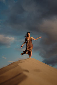 Low angle view of woman standing on sand against sky