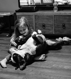 Girl playing with dog on floor at home