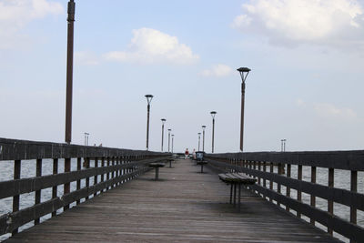 Pier on footbridge over sea against sky