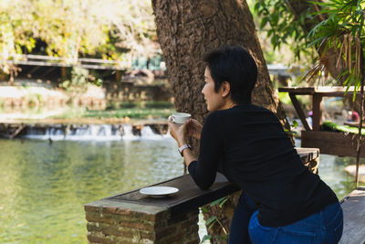 Side view of young woman standing by lake